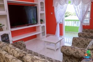 sala de estar con TV de pantalla plana y 2 sillas en EHL Grand 8Bed 9bath, Fully Furnished Air Conditioned Villa 5min to Beach, en Saint Phillip