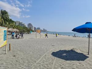una playa con una sombrilla azul y gente en ella en Casa Blanca del Mar en Santa Marta
