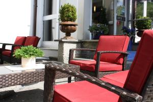 un groupe de chaises rouges assises sur une terrasse couverte dans l'établissement Hotel Cosima, à Vaterstetten