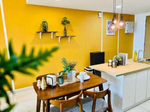 een keuken met een tafel met stoelen en een gele muur bij Gathering House Mosaic Midvalley 2BR 1K4Q 7-13px in Johor Bahru