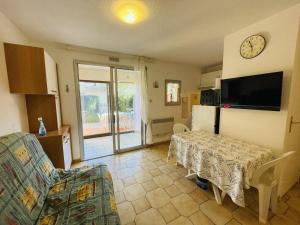 sala de estar con mesa y cocina con reloj en Appartement Cap d'Agde, 2 pièces, 4 personnes - FR-1-723-83, en Cap d'Agde