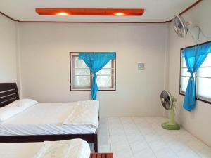 a bedroom with two beds and a window with blue curtains at The Ocean Phangan Homestay in Haad Rin