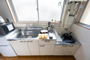 una pequeña cocina con fregadero y ventana en コーポウメザキ, en Ogikubo