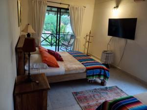 a bedroom with a bed and a television and a balcony at Fincas Panaca Herreria 1 - San Judas in Quimbaya