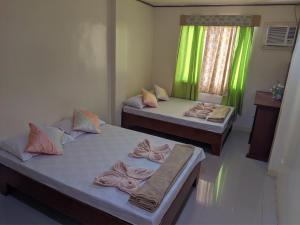 - 2 lits dans une chambre avec des rideaux verts dans l'établissement La Casa Milagrosa, à Coron