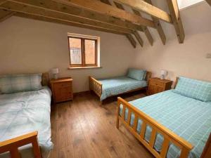 a bedroom with two beds and a chair and a window at Charming Norfolk Barn Conversion in Barnham Broom in Norwich