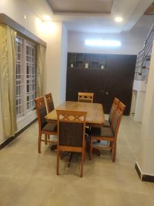 a dining room with a wooden table and chairs at Chill Breeze Castle - 4BHK Villa with Captivating city view & Mountain view, Wifi, Campfire, Homemade Food in Kodaikānāl