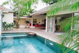 a house with a swimming pool in front of a house at The Decks Bali in Legian