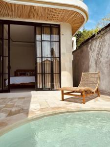 a pool with a chair next to a house at Emma’s Villa in Seminyak