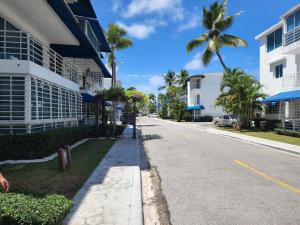 une rue en face d'un bâtiment avec des palmiers dans l'établissement 2 bedrooms, 2 bathrooms, pool and near from the beach, à Juan Dolio