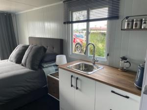 a small kitchen with a sink and a bed at Raglan Seaview Cabin in Raglan