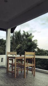 two wooden benches sitting under a building with palm trees at Tiara Homestay in Plambi