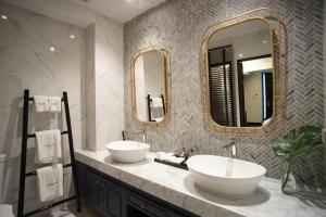 a bathroom with two sinks and two mirrors at Cheeva Dee Hotel in Chiang Mai
