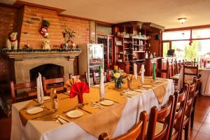 a dining room with a long table and a fireplace at Hostería San Clemente in Ibarra