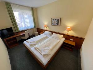 ディンゴルフィングにあるHotel-Gasthof Postbräu Dingolfingの大きなベッドとデスクが備わるホテルルームです。