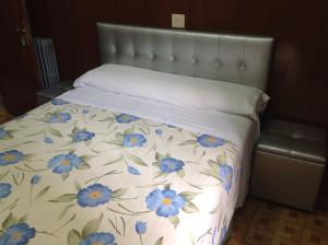 Una cama con una manta con flores azules. en Pension Estefania, en Salamanca