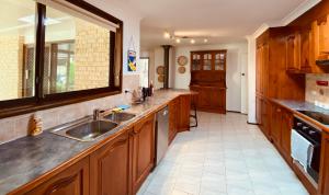a large kitchen with wooden cabinets and a sink at Relaxing at acreage farmhouse in Burrawang +27 photos