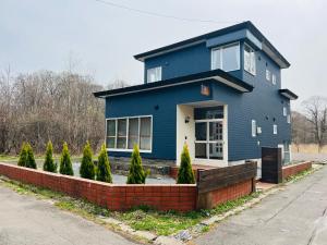una casa azul con una pared de ladrillo rojo en ヴィラYukara緑屋, en Nanae