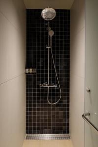 a bathroom with a shower with a black tiled wall at BEB5 Okinawa Seragaki by Hoshino Resorts in Onna