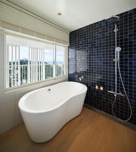 a bath tub in a bathroom with a window at BEB5 Okinawa Seragaki by Hoshino Resorts in Onna