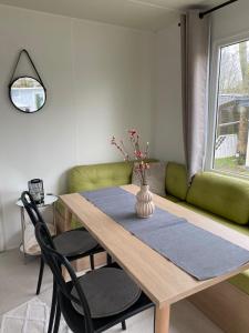 een eetkamer met een tafel en een groene bank bij WohlfühlChalet Makkum Ijsselmeer Familienunterkunft in Makkum