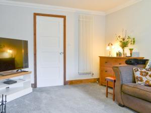 uma sala de estar com um sofá e uma televisão em Willow Cottage em Cockermouth