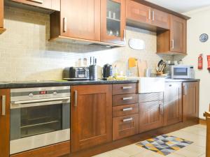uma cozinha com armários de madeira e um forno com placa de fogão em Willow Cottage em Cockermouth