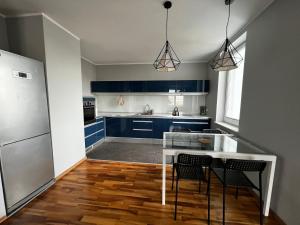 uma cozinha com armários azuis e uma mesa e cadeiras em Do Gdyni Exclusive em Gdynia