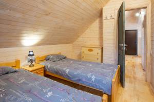 two beds in a room with wooden walls at Rāznas Stāvkrasti in Kaunata