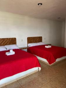 2 Betten mit roten Decken in einem Zimmer in der Unterkunft REBOLLEDO IMPERIAL in San Cristóbal
