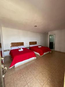 2 Betten in einem Zimmer mit roter Bettwäsche in der Unterkunft REBOLLEDO IMPERIAL in San Cristóbal