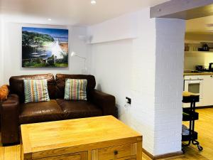 een woonkamer met een bruine bank en een tafel bij Cobble Cottage in Cramond