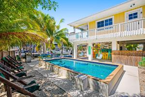 a swimming pool in front of a house with palm trees at Key Lime Time in Cudjoe Key