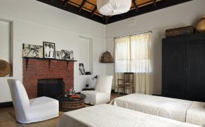 un soggiorno con 2 letti e un camino di Satyagraha House a Johannesburg