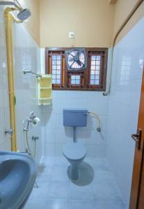 NALINAM HOMESTAY في تريفاندروم: حمام مع مرحاض ومغسلة وساعة