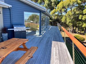 a wooden deck with a picnic table and a grill at Harbour Lookout in Strahan