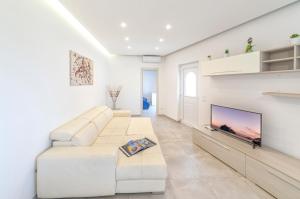 ein Wohnzimmer mit einem weißen Sofa und einem Flachbild-TV in der Unterkunft Casa Yucca in Ischia