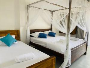 Duas camas num quarto com lençóis brancos e almofadas azuis em Rams Resort em Arugam Bay
