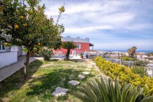 einen Garten mit Orangenbäumen und einem roten Haus in der Unterkunft Casa Yucca in Ischia