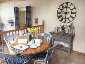 a dining room with a table and a clock on the wall at The Brae Steading in Fordyce