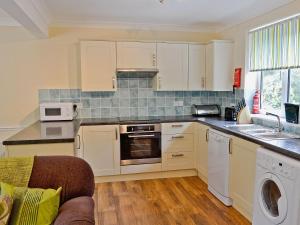 uma cozinha com armários brancos e um forno com placa de fogão em A Twist Of Lyme em Blackpool Corner