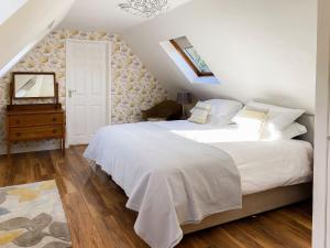 a bedroom with a large white bed and a wooden floor at A Twist Of Lyme in Blackpool Corner
