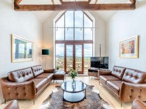 a living room with leather furniture and a large window at Haybale Barn in Chatton