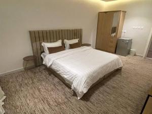 ein Schlafzimmer mit einem großen weißen Bett und einem Spiegel in der Unterkunft شاليه الندى in Chamis Muschait