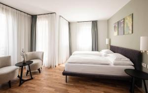 a bedroom with a large bed and two chairs and a table at Boutique Hotel Pachers in Bressanone
