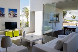 a living room with a white couch and a tv at B Blue Beachouses in Itacimirim