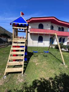 a playground with a swing set and a house at Villa Somma Apartments in Pimonte