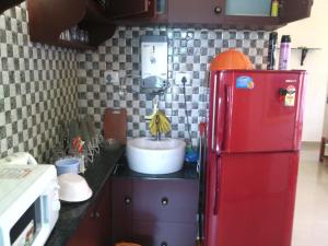 a red refrigerator in a kitchen with a sink at Nathans Holiday Home in Cochin
