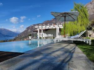 a house with a swimming pool with an umbrella at Villa Maria Laura in Lierna