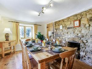 a dining room with a table and a stone wall at Honeysuckle Cottage in Axminster